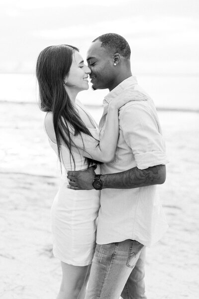 Man and woman laughing and getting ready to kiss on the beach in a Tampa engagement photography session.