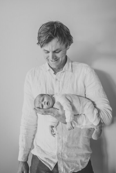 a newborn baby posing in dads hands during a newborn photoshoot in wanaka captured by Bie