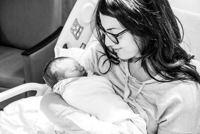 A black and white photo of Kala in her hospital bed holding her newborn baby.