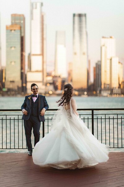 Image of a bride and groom on the pier, NYC skyline behind them