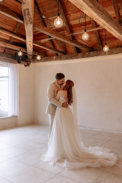Hochzeitspaar steht in einem Raum und umarmt und küsst sich