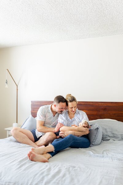 parents hold baby on their bed during at home newborn session in Santa Monica