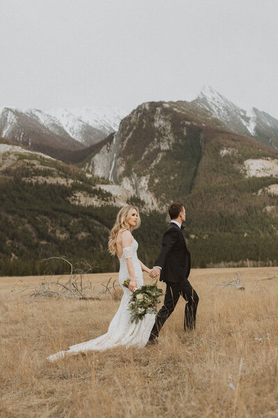 bride in long elopement dress on mountain holding bouquet