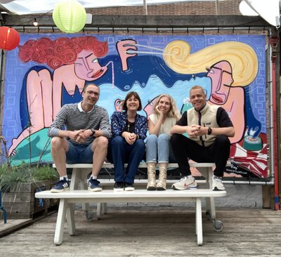A group of professionals talking in front of a colorful mural, symbolizing collaboration and leadership.