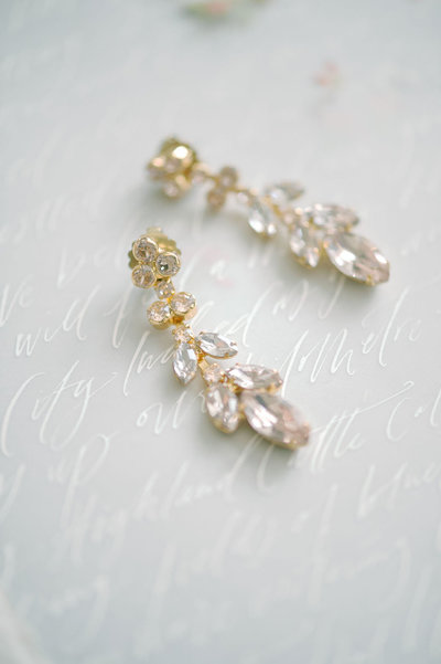 Crystal petal drip earrings from BHLDN atop calligraphed vellum vows
