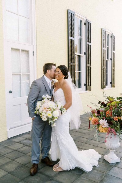 Bride and groom in front of colorful yellow house
