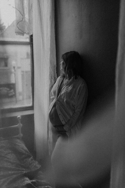 Pregnant woman holding her belly during an in-home maternity session in Michigan