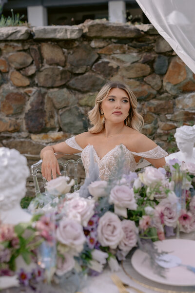 Wedding Photographer, a bride sitting at the table behind florals