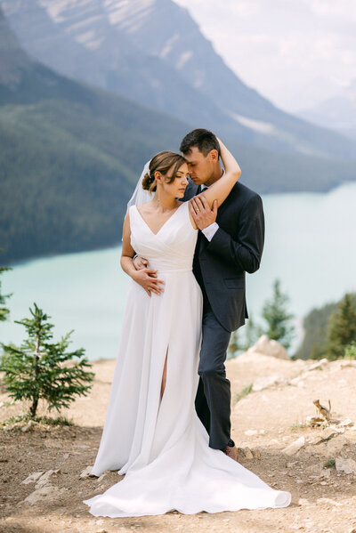 This evocative image captures a newly married couple at Peyto Lake, with the groom standing behind his bride, enveloping her in a warm and passionate embrace. The vivid turquoise waters of the lake and the majestic backdrop of Banff National Park frame their first moments as husband and wife, reflecting the depth and beauty of their bond.