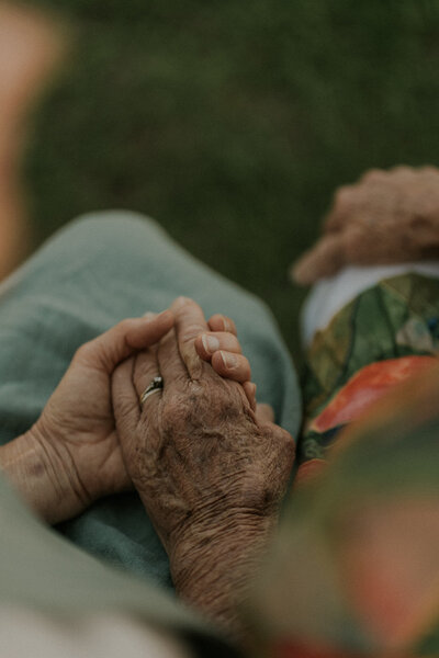 A touching family photo of an older person holding hands with someone in her family during their photo shoot in Grafton