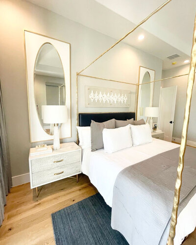 A bedroom decorated with minimalist and elegant grey and white tones, featuring two large mirrors, bedside lamps, and stylish furnishings, showcasing personalized interior design services in Frisco.