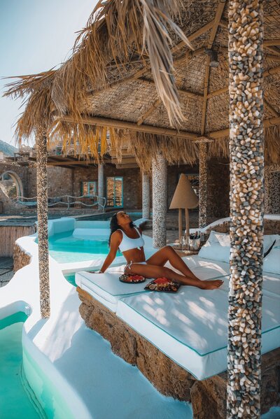 Zee James sunbathes on a white chaise lounge at a tropical resort