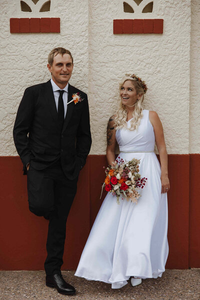 Bride and groom captured in a relaxed Sunshine Coast wedding portrait with vintage wall backdrop.