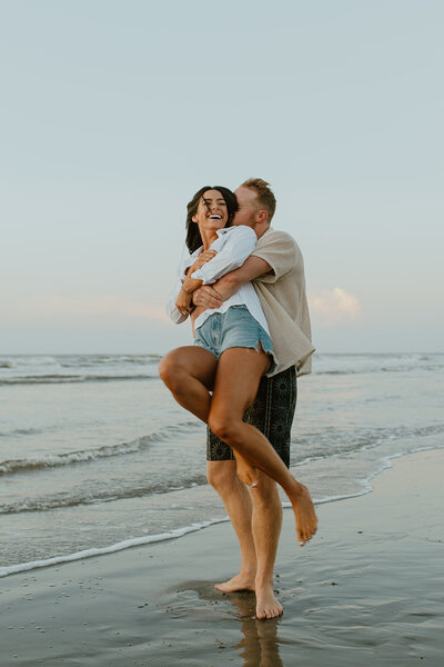 man spins wife around beach