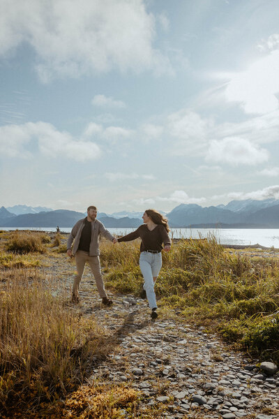 couple holding hands as they run on the beach at their engagement session