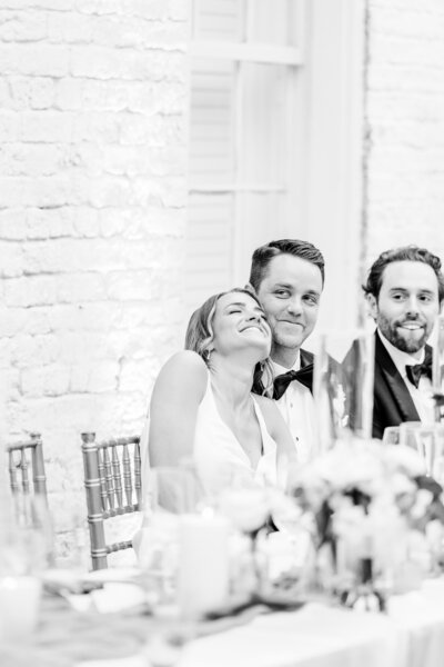 candid black and white photo of bride leaning on groom during toasts