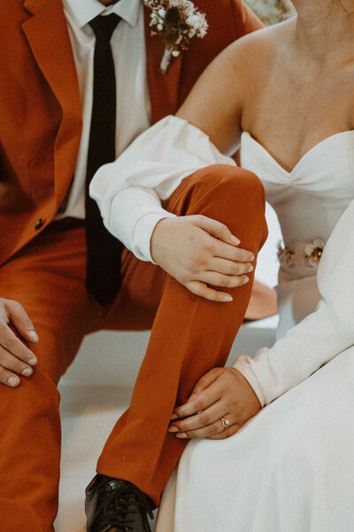 bride in white gown and groom in terracotta suit