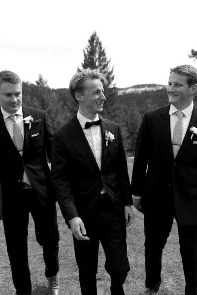 Black-and-white candid photo of groomsmen walking together outdoors at Woodlands Colorado — Colorado wedding party portrait