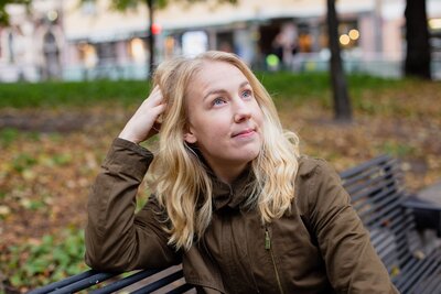 Hyvinvointivalmentaja hymyilee penkillä istuen