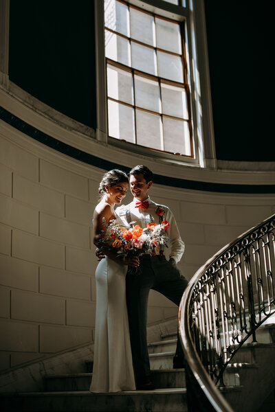 Couple posing in the sunlight inside of Portland City Hall in Portland Maine
