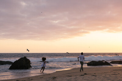 a couple running on the beach in California at sunset during a candid and adventurous engagement session