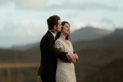 A couple cuddle and kiss during golden hour at the end of their elopement in Glencoe, Scotland