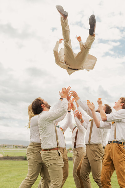 Groom being tossed in the air during his wedding in Logan, Utah