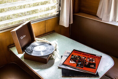 Place branding photo closeup portable record player with records on table inside mini airstream photo Gatos Trail Ranch California desert