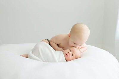 big brother looking down at little brother on white bean bag
