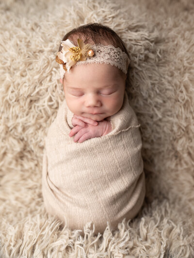 newborn baby girl wrapped in beige for studio portraits