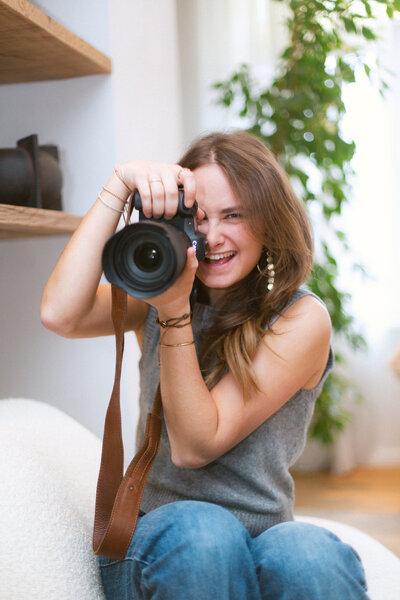 Candid shot of Bo Eppink, smiling while capturing a moment with her camera, showcasing her passion and joy for photography.