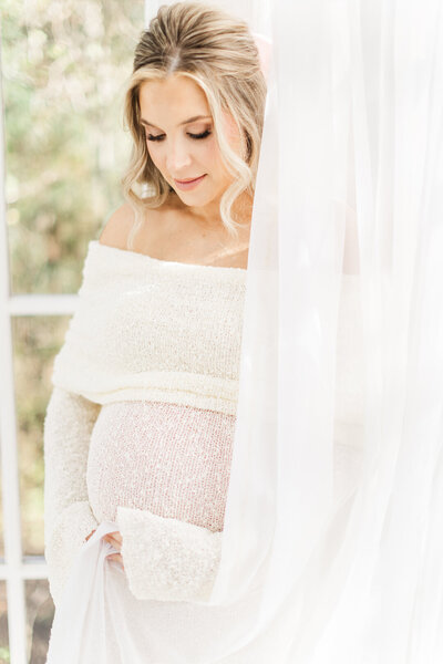 expecting mother holds belly for maternity photo session