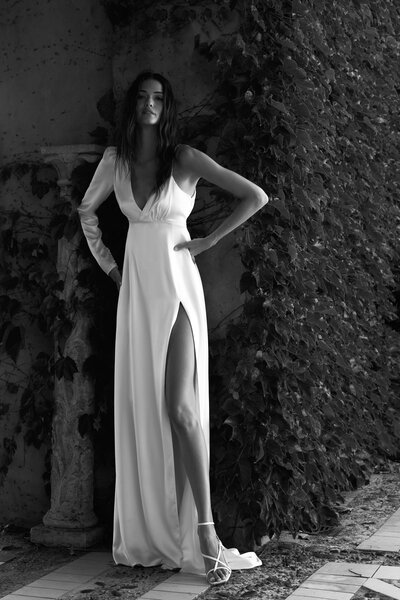 black and white image bride wearing satin wedding dress with high slit