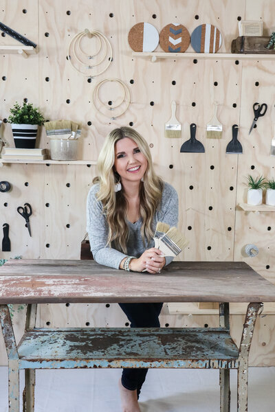 woman smiling holding paintbrushes