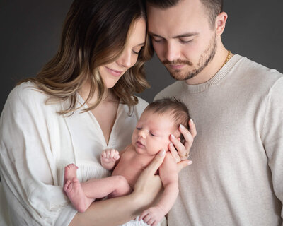 studio portrait of new family in neutrals with newborn closeup with grey backdrop