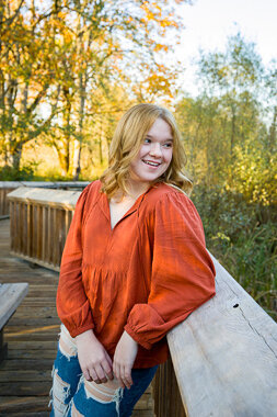 Graduating high school senior girl with an orange shirt looking over her shoulder in Olympia WA