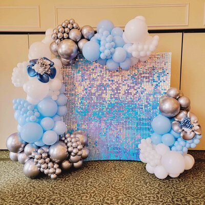 The event space with the enchanting allure of our Shimmer Blue and White Wall adorned with a Half Arch of Balloons. Air with Flair Decor's expertly crafted installation brings sophistication and charm to any occasion.