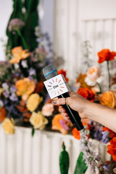 Branded microphone in front of bright wedding floral arrangement, capturing the energy of Austin corporate event design.