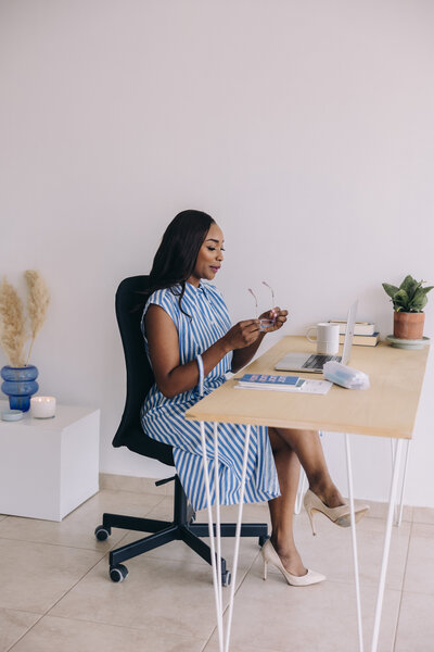 woman sitting at desk holding glasses