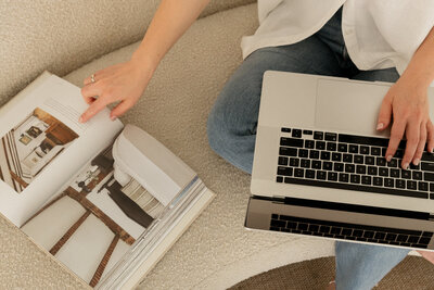 Female sitting on couch with laptop and a design book