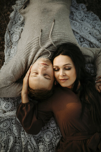 couple lays on vintage blanket with eyes closed for photo