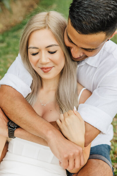 engaged couple on grass cuddling