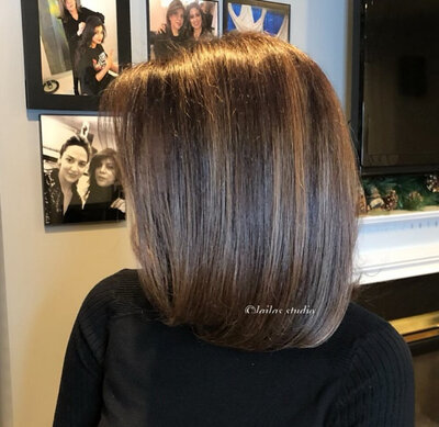 A client from Laila's Studio showcasing their freshly cut and styled brown hair from the back, appearing healthy and sleek.