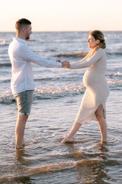 Zwangerschapsshoot Leiden op het strand met zwangere vrouw en man in de zee