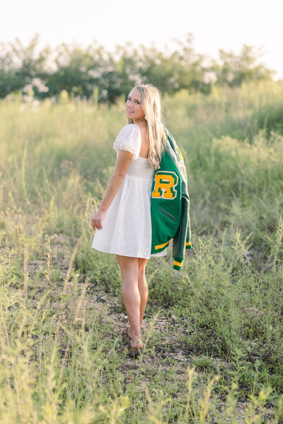 high school senior holding her letter jacket at Sculpture Fields