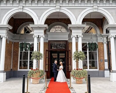 bride and groom facing each other and holding hands in front of the Oatlands Park Hotel in Surrey