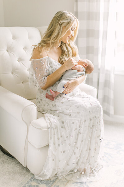 Mom holding her baby inside her white nursery