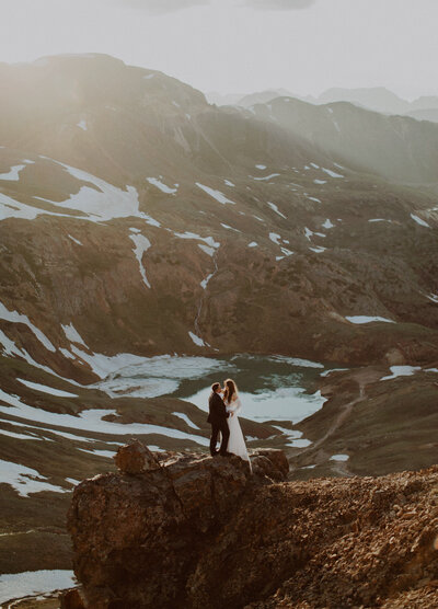 Bride and groom elope on a cliff overlooking an alpine lake