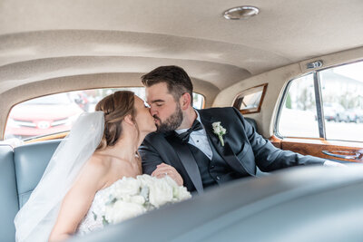 A bride and groom kiss in a vintage car at the Avenir in Walpole.