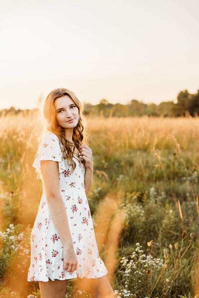 oshkosh senior Ashley standing in a grassy field at sunset